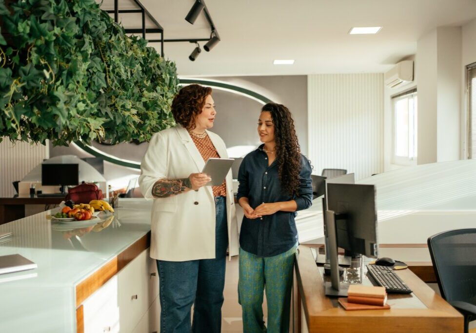 Two women standing in an office, talking to each other